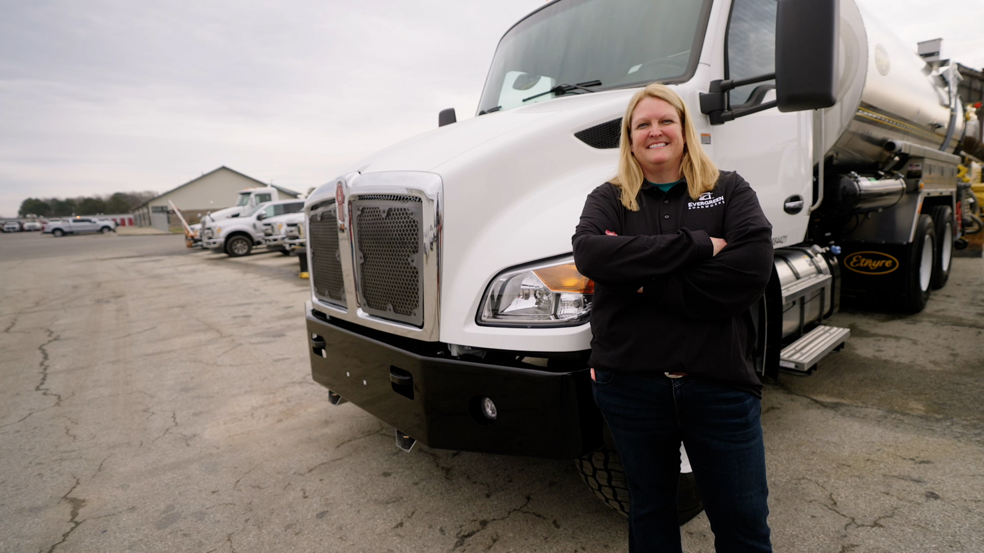 Ann winning of woman in construction stands in front of an asphalt truck