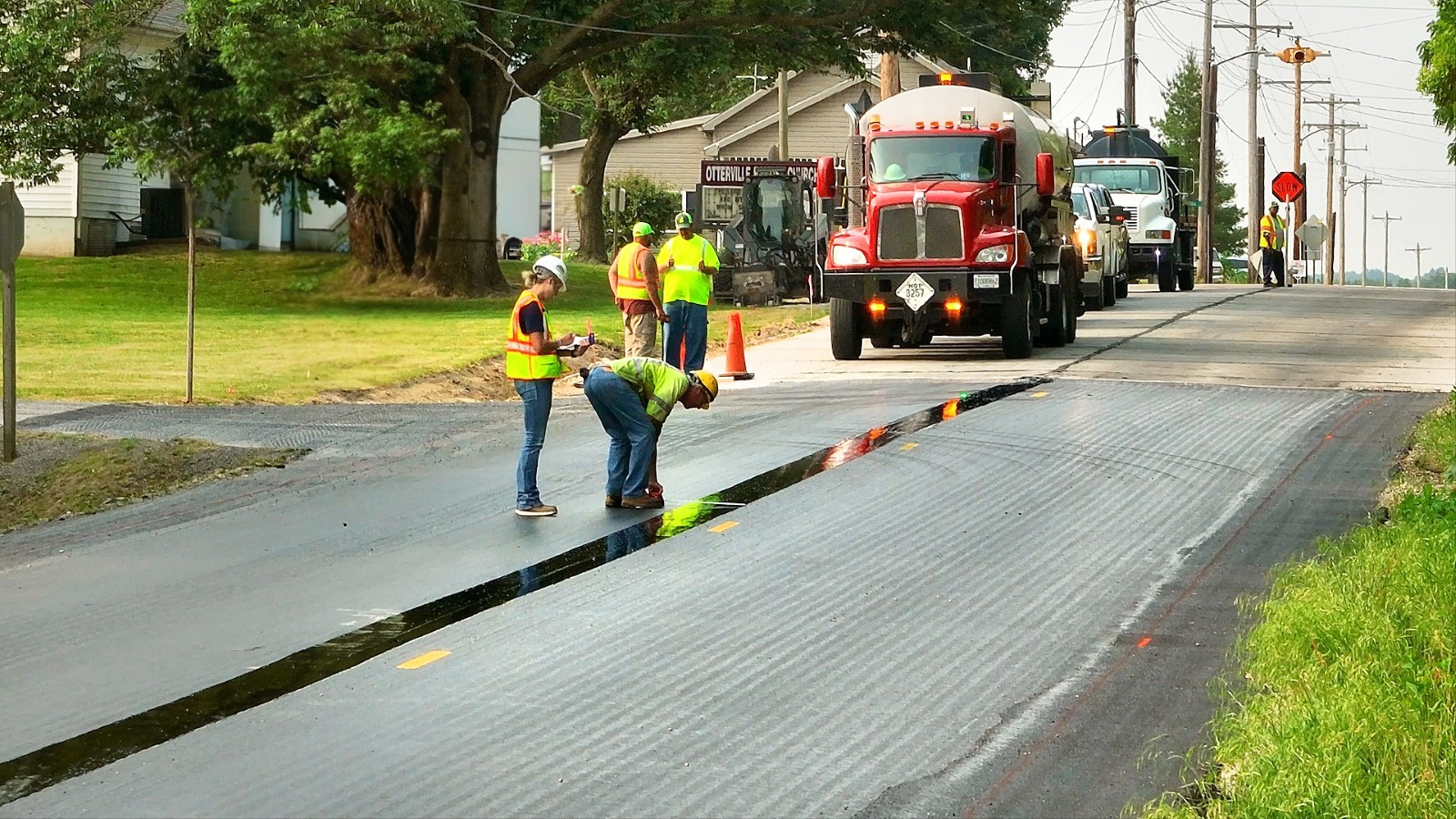 Road Construction crew examines freshly laid band of J-Band, a Longitudinal Joint Seal