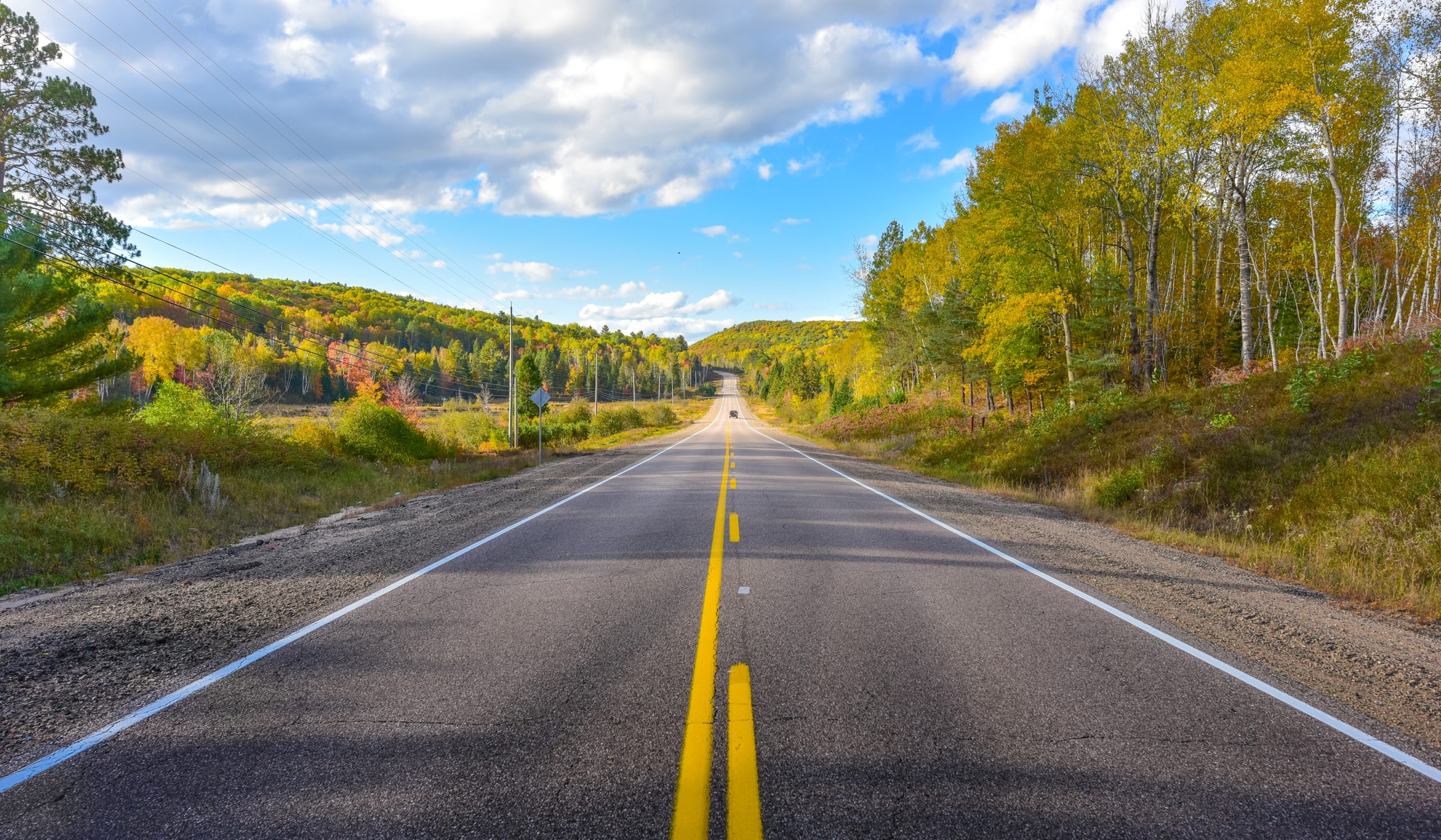 Looking down a sunny asphalt highway, thinking about the origins of americas roads